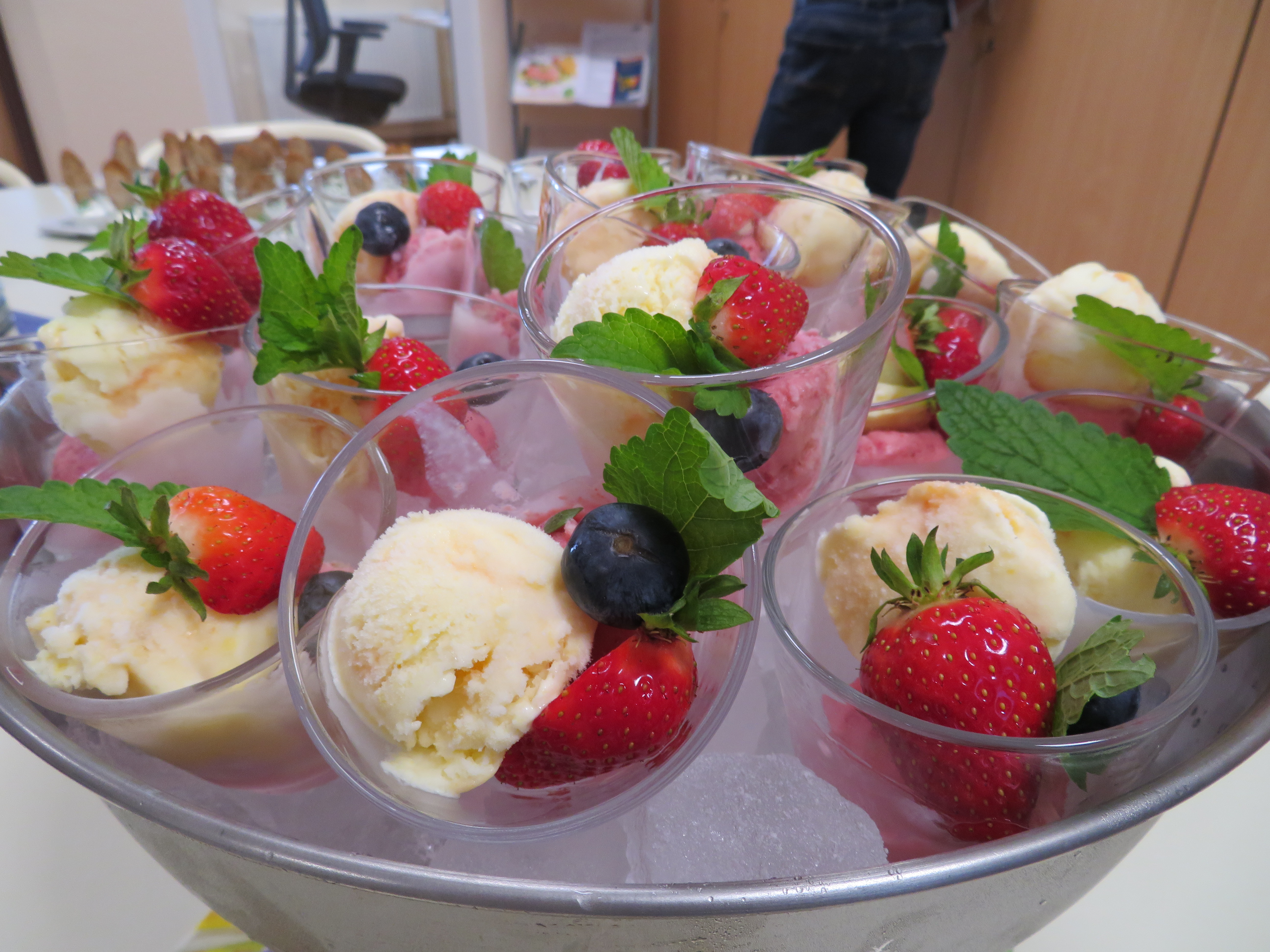 Eistassen mit Erdbeeren, Heidelbeeren und Minze in einer Kühlbox auf Eis.